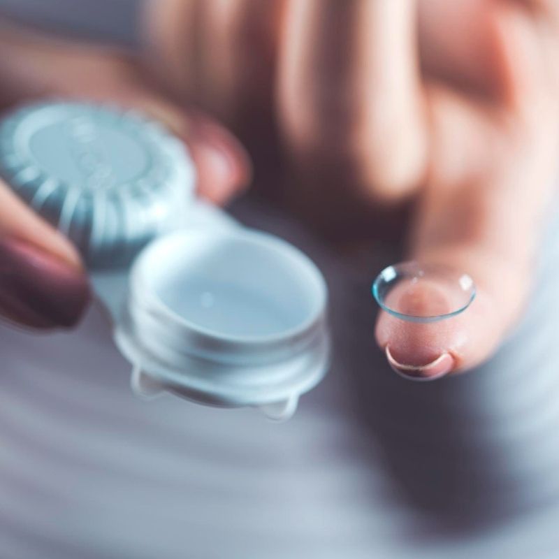 Contact lens resting on a fingertip before placement